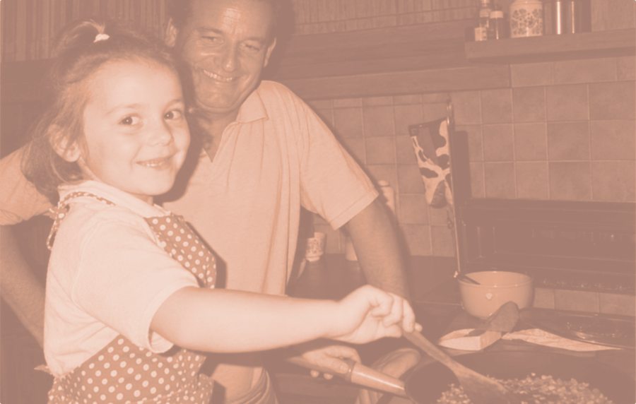 Aurélie as a little girl in a polka-dot apron, stirring a pan with her dad